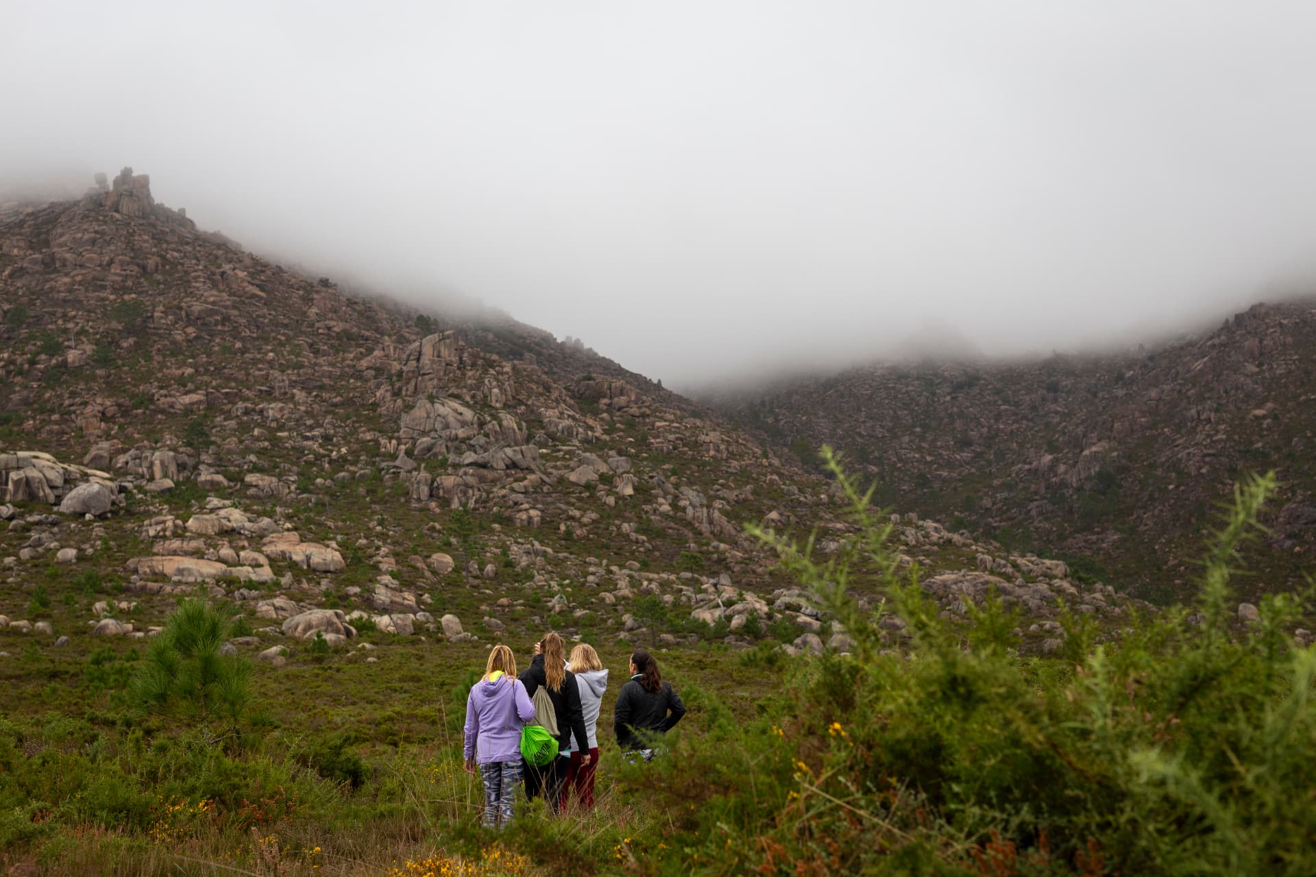 Grupo de sendeiristas na contorna de O Pindo, Carnota, coa montaña e a néboa de fondo