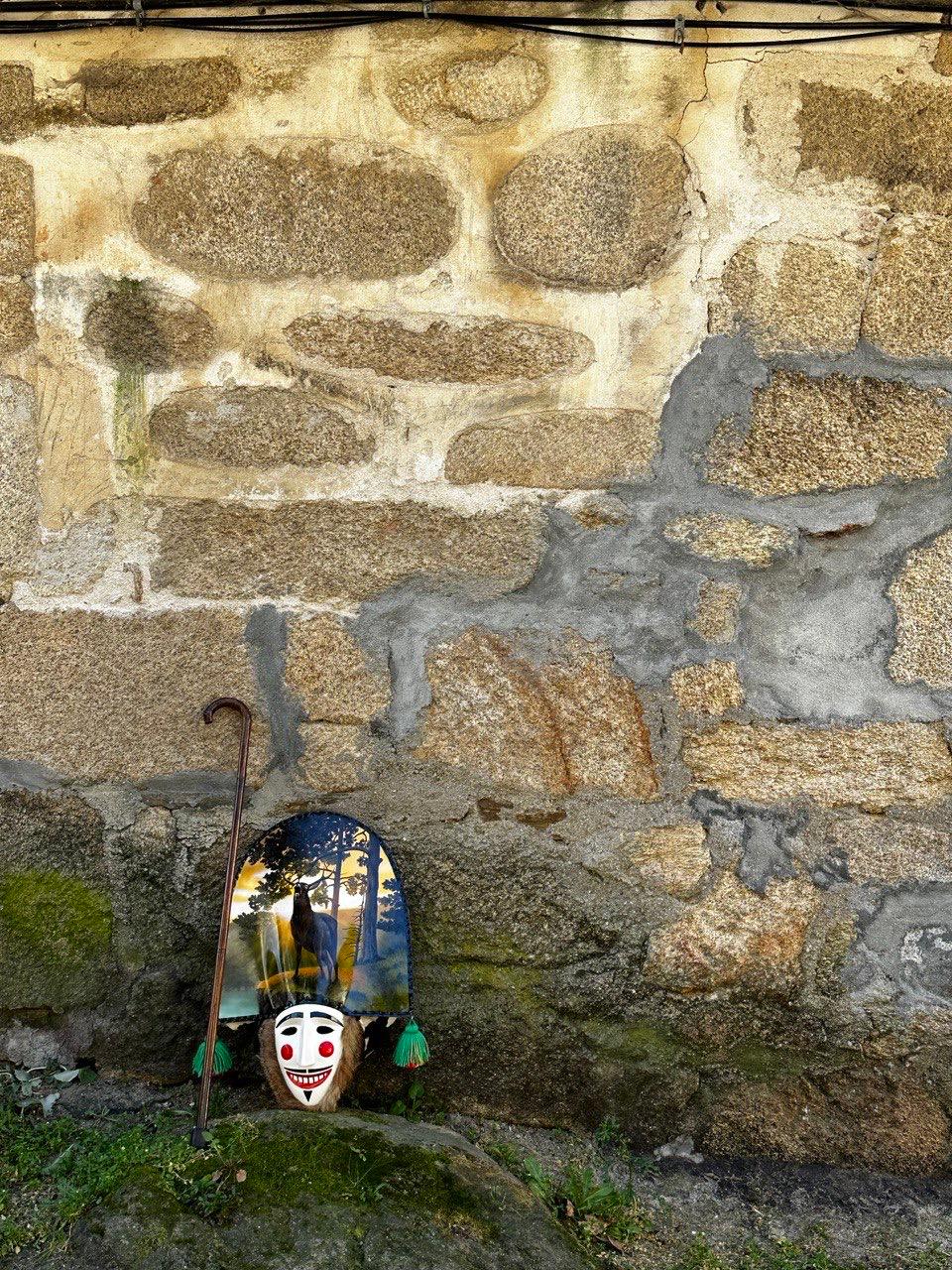 Máscara tradicional do entroido galego xunto a unha parede de pedra